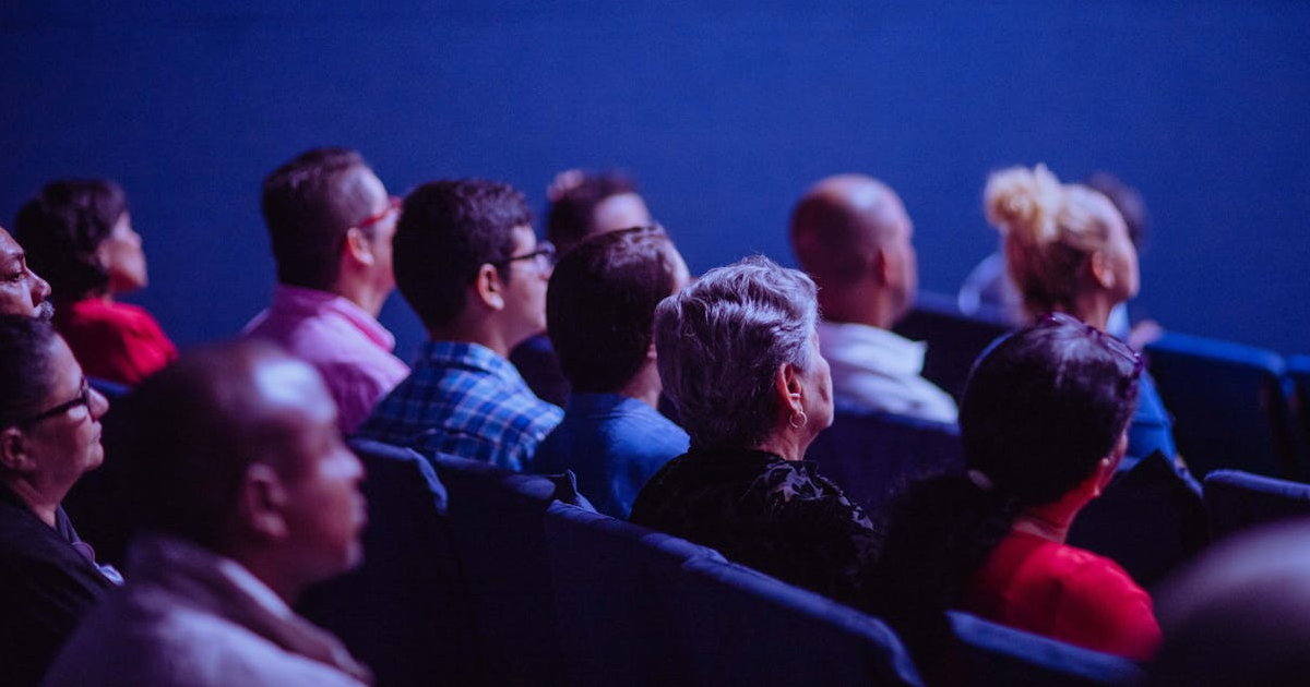 A photo of a seated audience looking forwards towards a speaker.