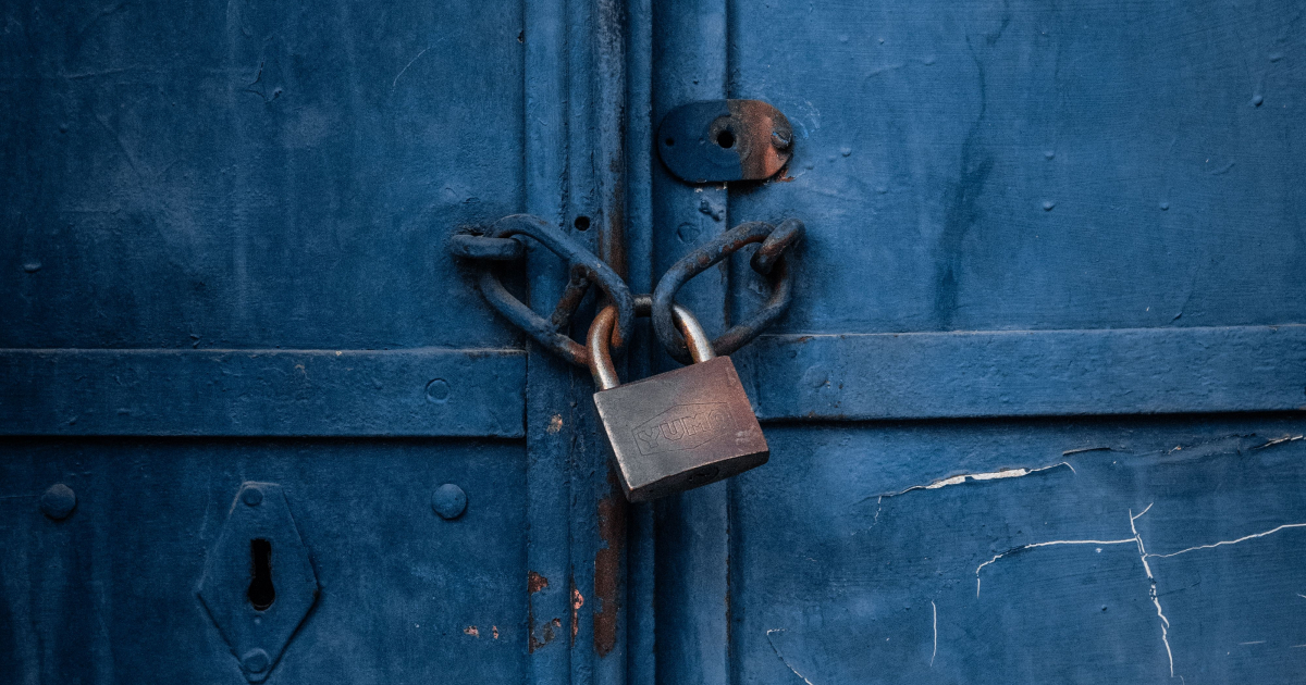 A photo of a padlock on a green bi-fold door.